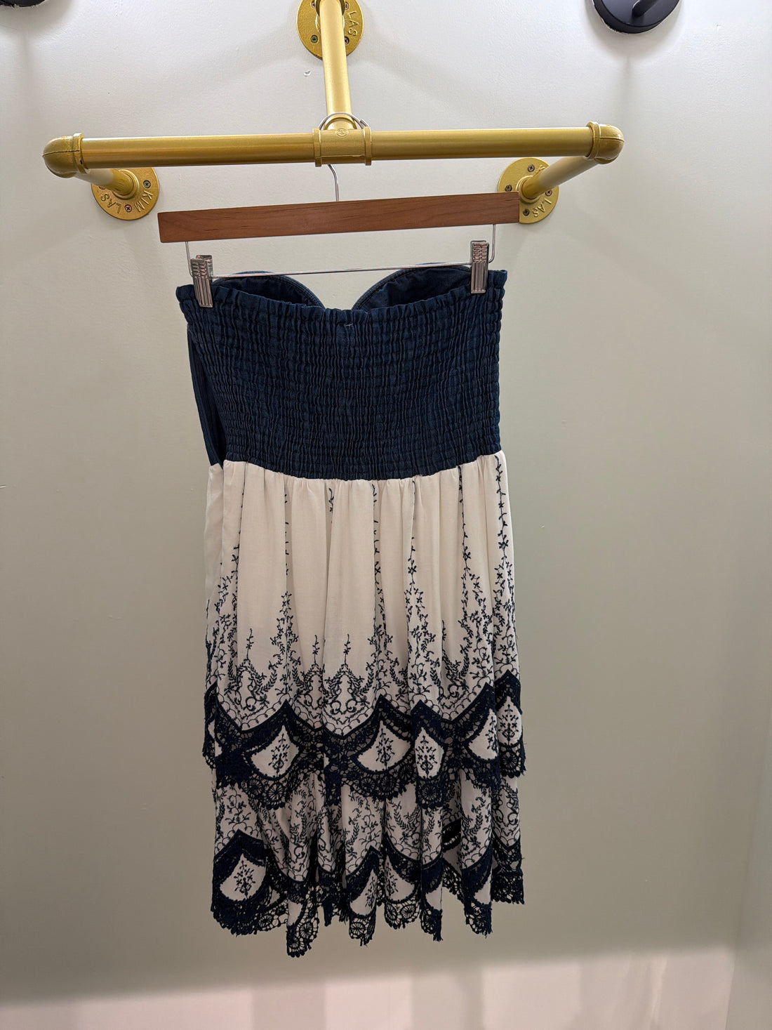 Strapless denim-bodice dress featuring a cream skirt with intricate navy embroidery and scalloped tiers.